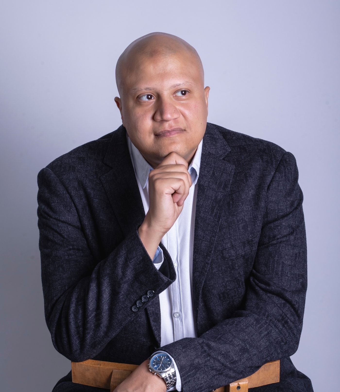Mohamed Elsherif, seated, in a dark jacket against a pale studio background.